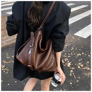 Detail of dark coffee brown leather tote with grainy texture and functional zippers
