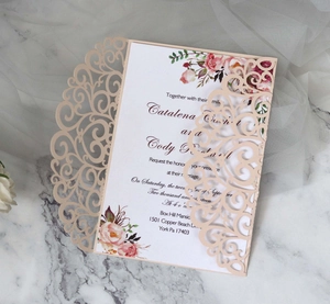 Detail of laser-cut peach wedding invitation with vintage floral print and elegant lace texture