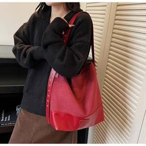 Detail of red suede bucket bag with adjustable metal eyelet strap on model