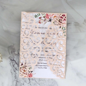 Detail of laser cut lace wedding invitation in light pink with watercolor roses