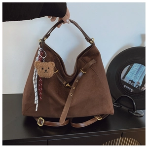 Vista dettagliata della borsa tote in pelle scamosciata marrone scuro con ciondolo a orso