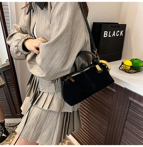 Close-up of black suede crossbody bag with premium gold ring hardware and metal zipper