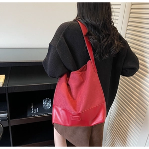 Detail of red faux suede tote bag with leather patchwork and embossed brand logo