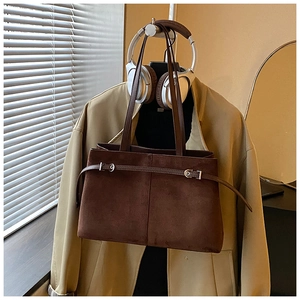 Vue détaillée d'un sac cabas en daim marron avec boucle sur un trench-coat beige