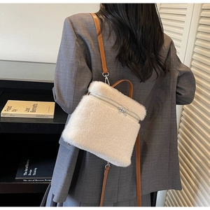 Detail of white plush backpack featuring brown leather straps and silver metal hardware