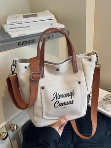 Minimalist beige canvas tote bag with brown leather handles and adjustable strap