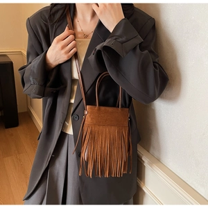 Détail d'un sac bandoulière vintage en daim marron avec de longues franges et une sangle