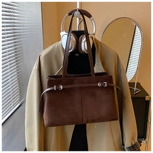 Gros plan du sac cabas marron foncé en daim synthétique avec boucles métalliques