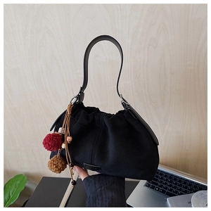 Détail du sac seau en daim noir avec pompons en fourrure colorés et perles en bois