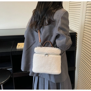 White faux fur bag detail featuring brown leather straps and dual zipper closure on a model
