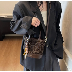 Close-up of leopard print bucket bag with gold logo and bohemian beaded accessory