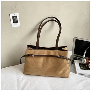 Détail du grand sac cabas en daim camel avec anses marron et accessoires de bureau