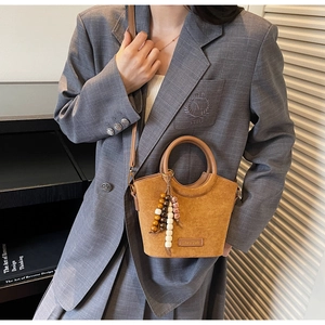 Brown suede bucket bag detail with colorful wooden bead charm and round handle