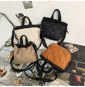 Quilted bucket bags in black, beige, khaki, and orange shown on a metal display rack
