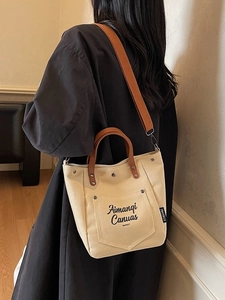 Minimalist canvas tote bag with brown leather handles and adjustable shoulder strap for women