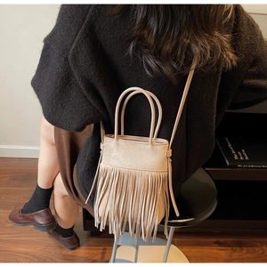 Détail du sac seau en daim beige avec de longues franges et une poignée supérieure pratique