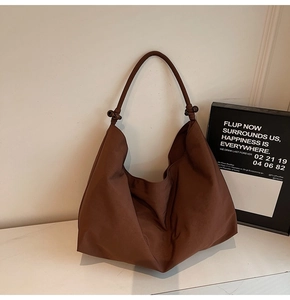 Close-up of deep brown hobo bag featuring smooth texture and decorative shoulder knots