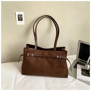Détail d'un grand sac cabas en daim marron avec de longues bandoulières et une boucle en métal