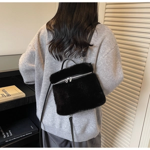 Detail of black faux fur crossbody bag with silver zipper and leather shoulder strap