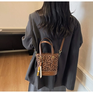 Detail of leopard print bucket bag with wooden bead pendant and brown leather shoulder strap