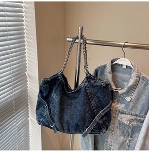 Detail of vintage blue denim tote bag with metal chain strap and decorative buckles