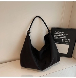 Detail of black large capacity hobo bag with thick rope shoulder strap and bead accents