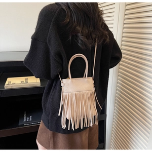 Détail du sac bandoulière rose à franges avec texture daim porté par un mannequin