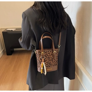 Detail of leopard print bucket bag with wooden bead charm and gold logo bottom