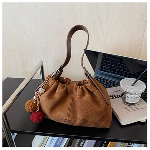 Vue détaillée du sac seau en daim marron avec lanière en cuir et breloques