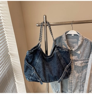 Detail of blue washed denim tote bag with silver metal chain and leather woven strap