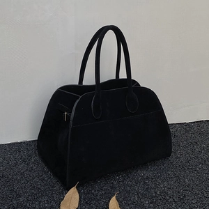 Dettaglio della borsa ventiquattrore in camoscio nero con fibbie dorate e trama