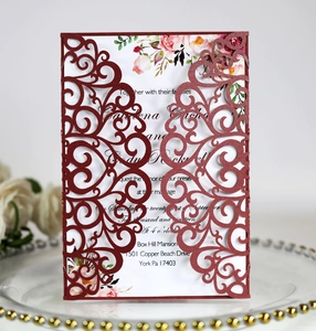 Detail of burgundy laser-cut wedding invitation lace cover with floral inner card