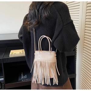 Vue détaillée du sac seau à franges beige clair avec texture de cuir mat et bandoulière