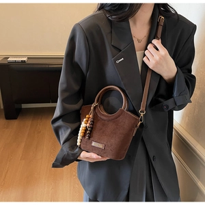 Brown suede crossbody bag with round wooden handle and colorful beaded charm