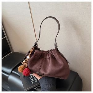 Vue détaillée du sac à bandoulière en daim marron avec texture plissée et breloque colorée