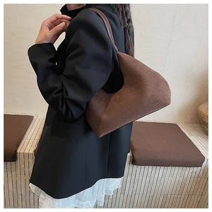 Detailed view of dark brown suede hobo bag with sleek leather strap on a model