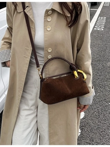Vintage brown suede handbag with gold chain detail, worn crossbody by a model in a beige coat