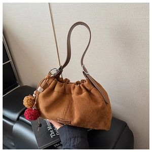 Détail du sac seau en daim marron avec design plissé et pompons décoratifs colorés