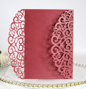 Macro shot of burgundy laser-cut lace wedding invitation with pearlescent finish