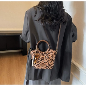 Detail of leopard print bucket bag with round handles and beaded tassel accessory
