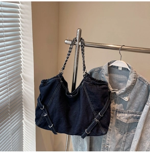 Detail of dark blue denim tote bag with metal chain handle and buckle decoration