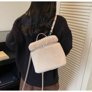 Detail view of a cream faux fur crossbody bag with metal zipper and slim strap