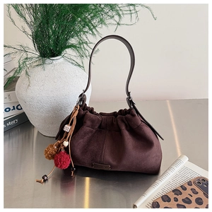 Détail du sac seau en daim marron avec poignée en cuir et breloques en perles colorées