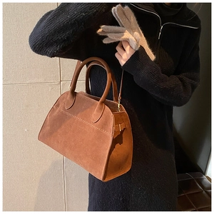 Dettaglio della borsa a cartella in pelle scamosciata marrone con texture morbida