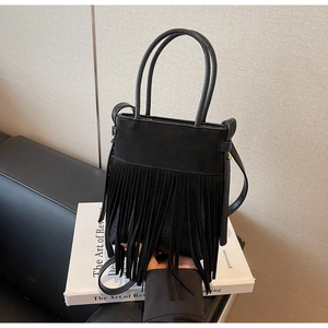 Gros plan d'un sac à franges noir en daim avec rivets dorés et bandoulière en cuir