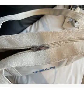 Détail de la fermeture éclair métallique fluide sur un grand sac cabas en toile écrue