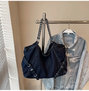 Close-up of vintage blue denim tote with woven chain strap and metal buckle details