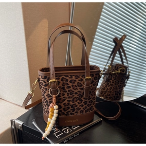 Detail of leopard print bucket bag with brown leather handle and colorful beaded charm