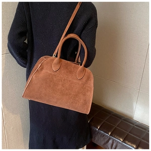 Dettaglio della borsa in pelle scamosciata marrone con manici tondi e tracolla regolabile