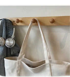 Détail de la texture en toile épaisse et des poignées robustes du grand sac fourre-tout blanc
